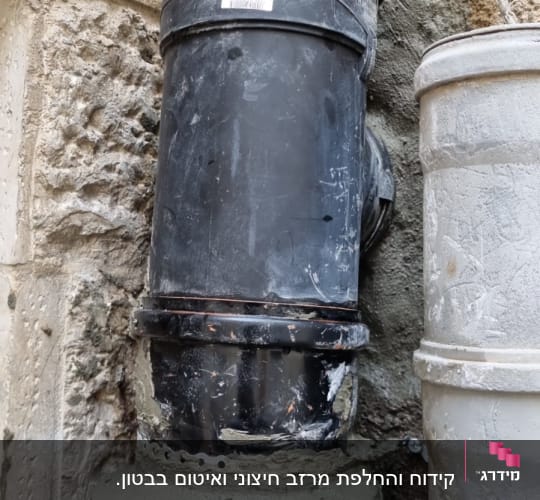 צינור שחור מחובר לקיר עם בטון